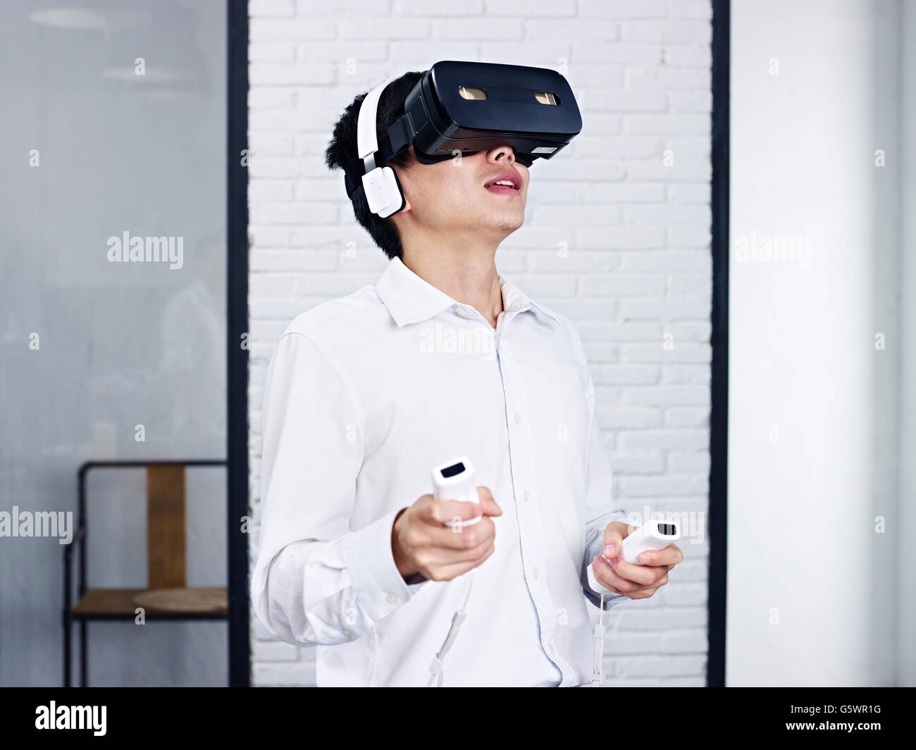 young asian man playing game with virtual reality (VR) goggles. Stock Photo