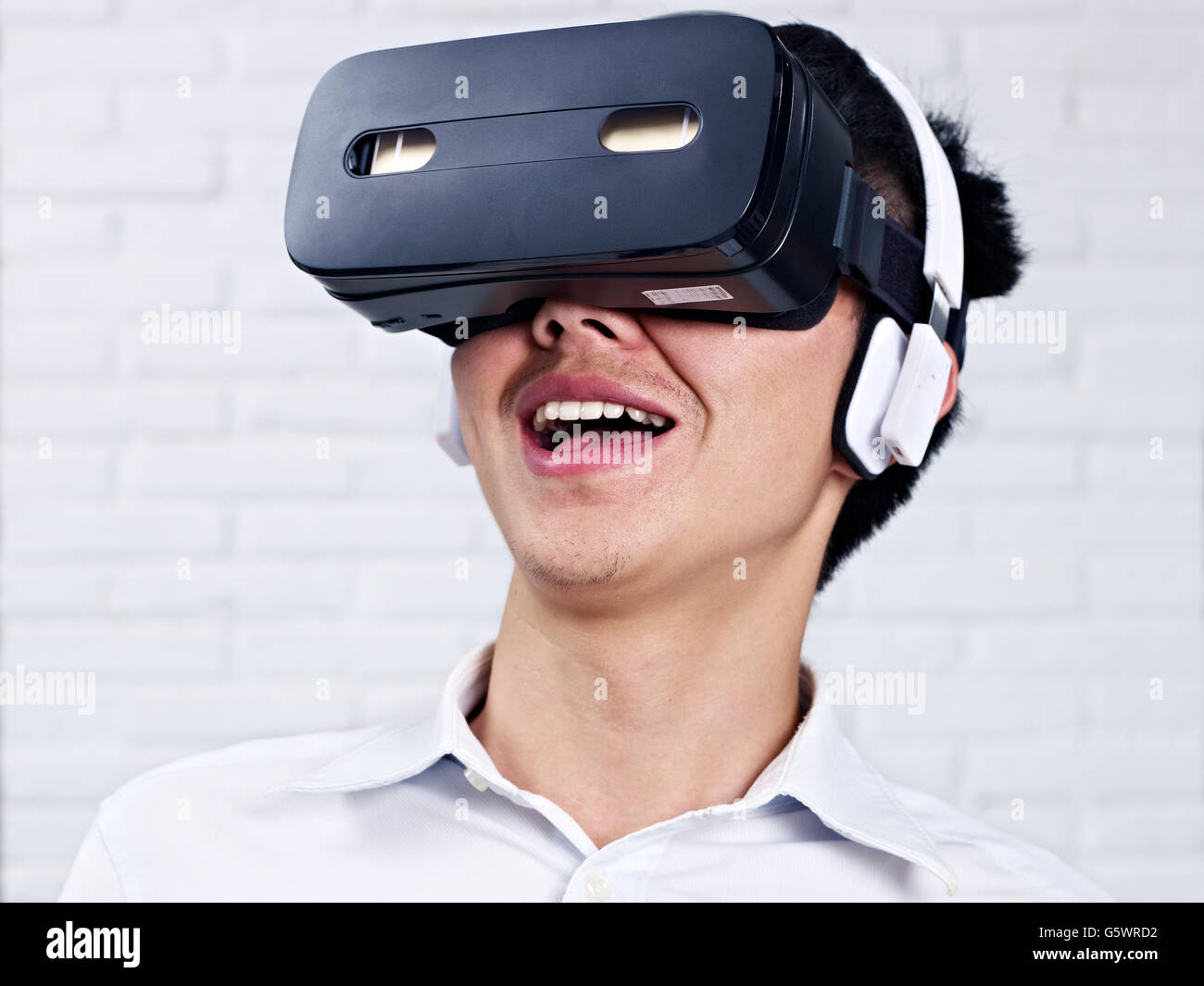 young asian man wearing head-mounted virtual reality (VR) goggles. Stock Photo