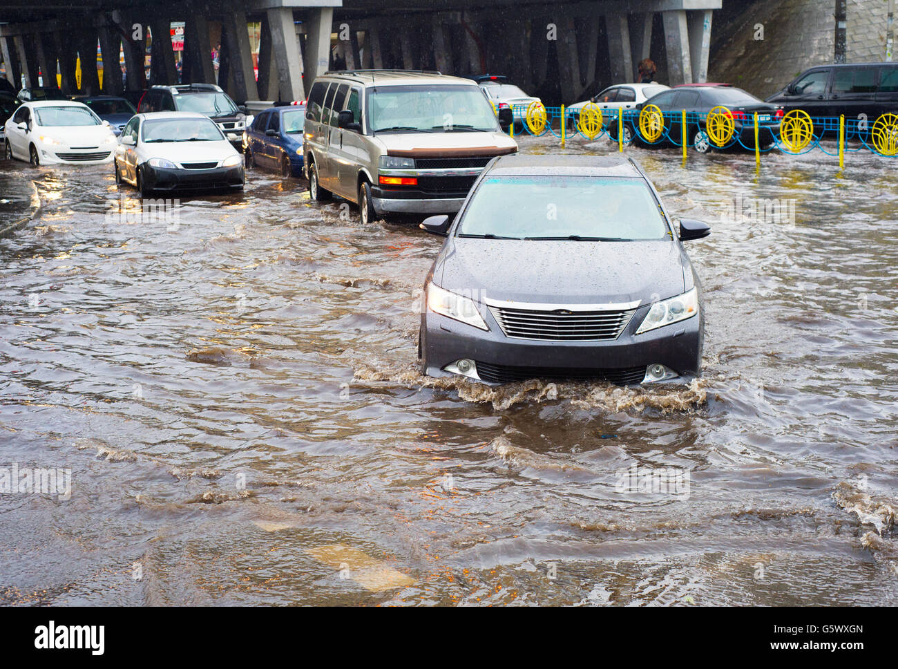 Car traffic in a heavy rain on a flooded city road Stock Photo