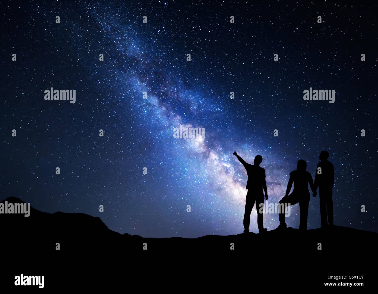 Colorful Milky Way with silhouette of a standing man pointing finger in night starry sky and his parents. Silhouette of a family Stock Photo