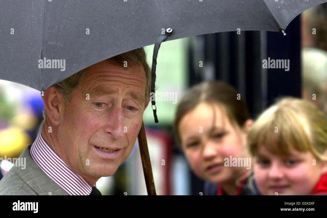 The Prince of Wales, Prince Charles, shelters from the elements during a walkabout in Liskeard Town Centre, Cornwall. Colourful Jubilee bunting remained in place to welcome the Prince of Wales to his duchy. * Charles who is Duke of Cornwall made his first stop at Liskeard to officially open a new museum and tourist information centre at the renovated, historic Foresters Hall. Charles greeted museum volunteers before unveiling a plaque to officially open the building. Stock Photo
