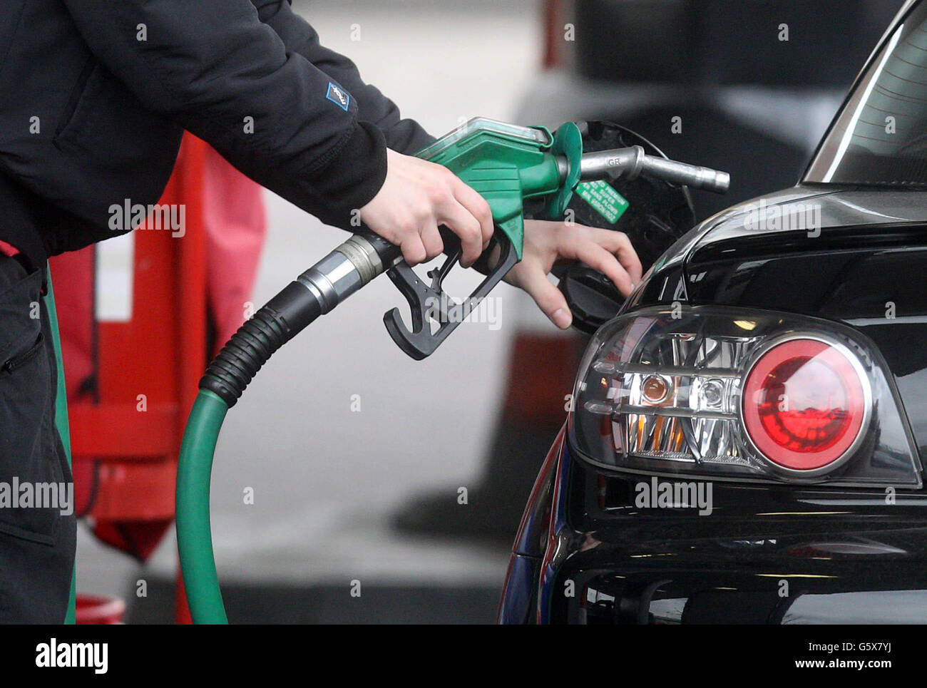 A generic photo of a person using petrol pump at a petrol station in