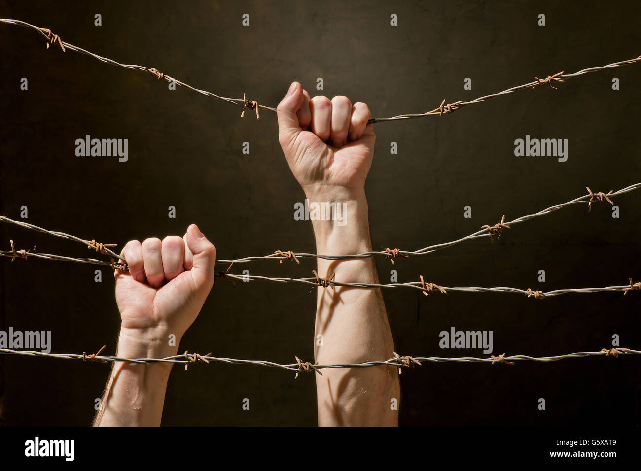 hand behind barbed wire with dark background Stock Photo