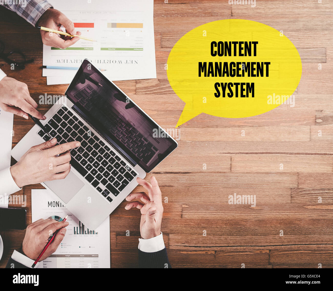 BUSINESS TEAM WORKING IN OFFICE WITH CONTENT MANAGEMENT SYSTEM SPEECH BUBBLE ON DESK Stock Photo