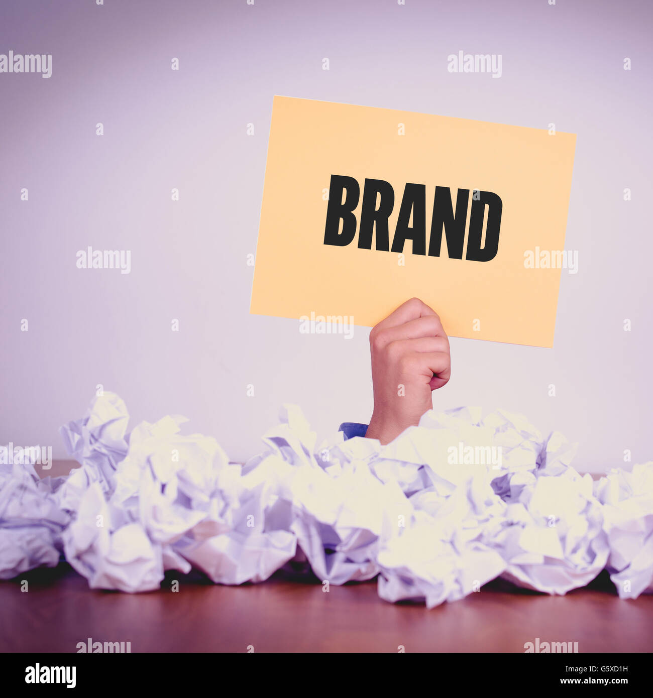 HAND HOLDING YELLOW PAPER WITH BRANDCONCEPT Stock Photo