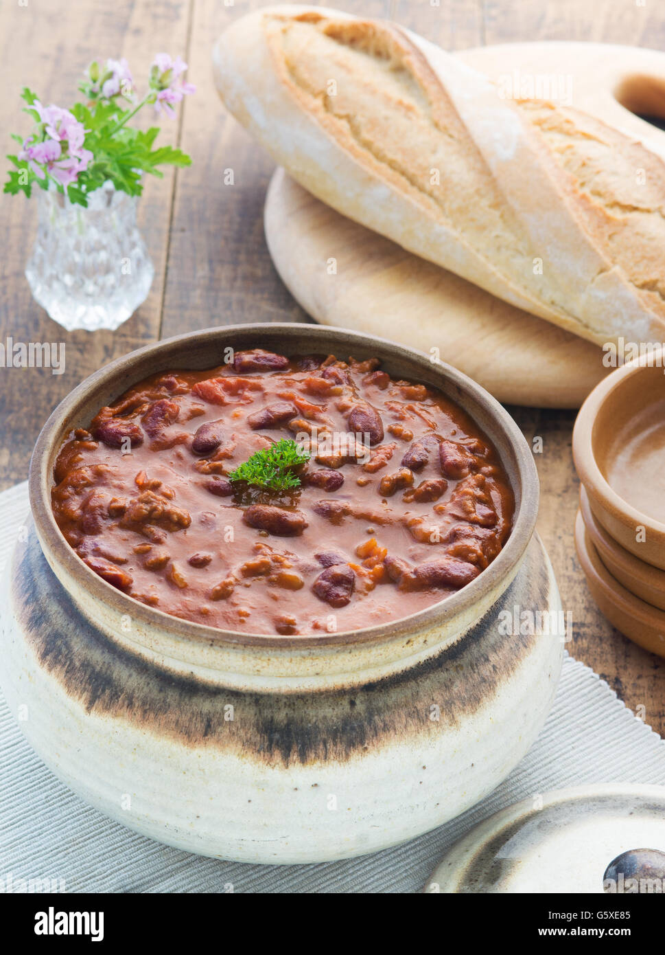 Top view of chilli con cane meal ,selective focus shot in a wooden table in a place setting with bread and plates Stock Photo