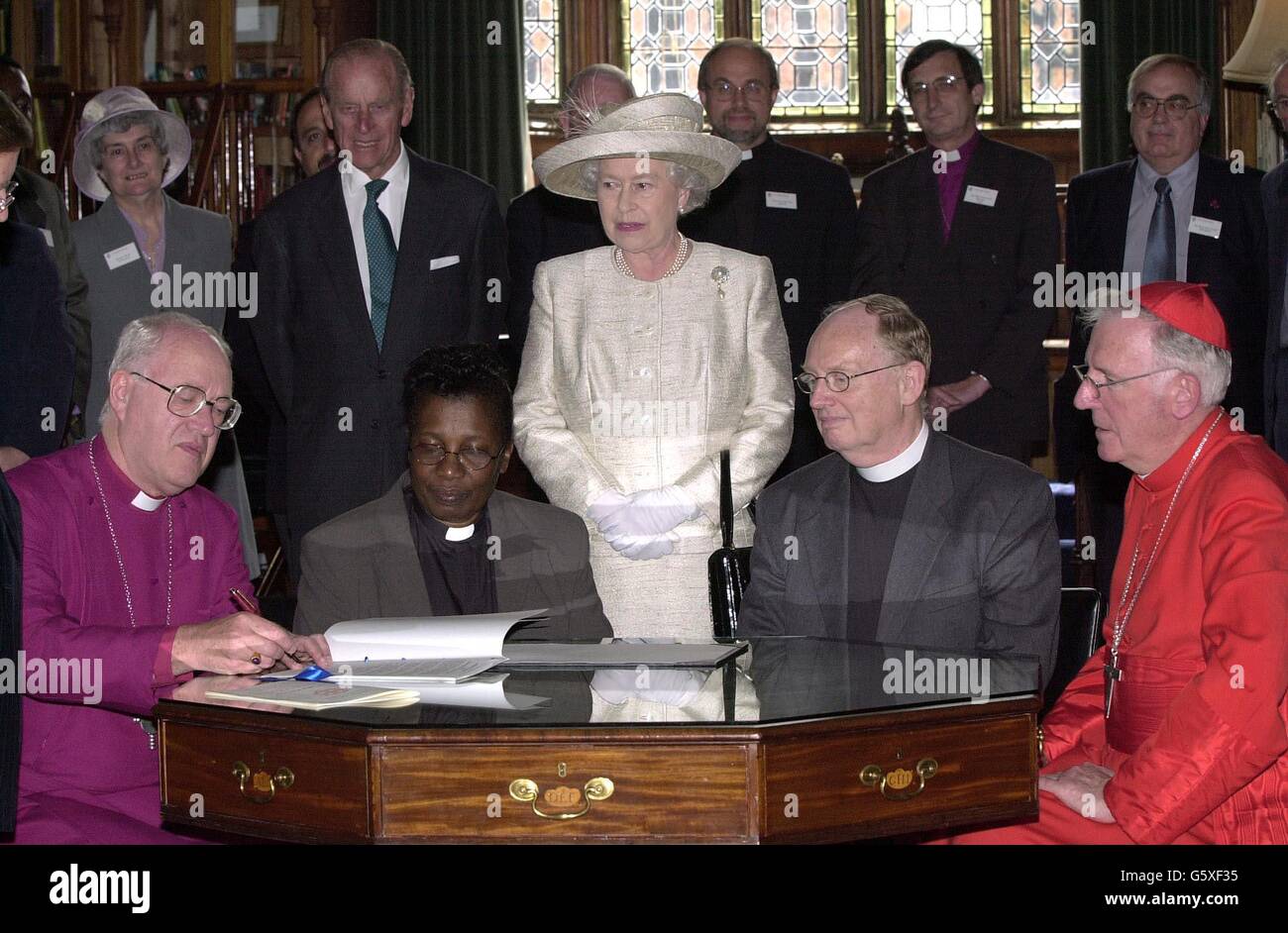 Queen Elizabeth II and the Duke of Edinburgh watch church leaders (L-R) Archbishop of Canterbury Doctor George Carey, Doctor Esme Beswick who represents Churches Together in England and Doctor Tony Burnham, the Moderator of Free Churches and Cardinal Cormack Murphy-O'Connor, Roman Catholic Archbishop of Westminster, sign an historic covenant to work towards furthering Christian unity at St Georges Chapel in the grounds of Windsor Castle, Berkshire following first-ever ecumenical church service at the chapel. * to mark the Queen's Golden Jubilee. Stock Photo
