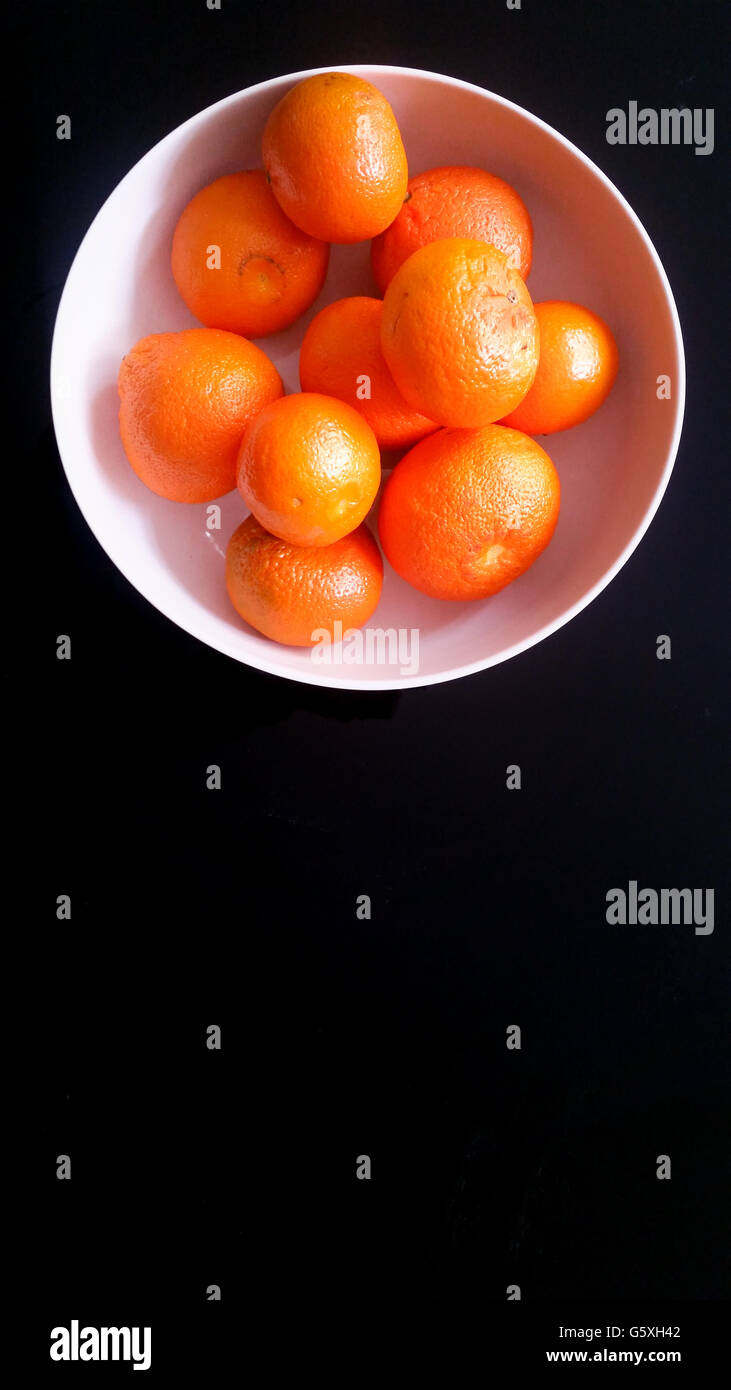 Tangerines in a White Bowl on a Black Background Stock Photo
