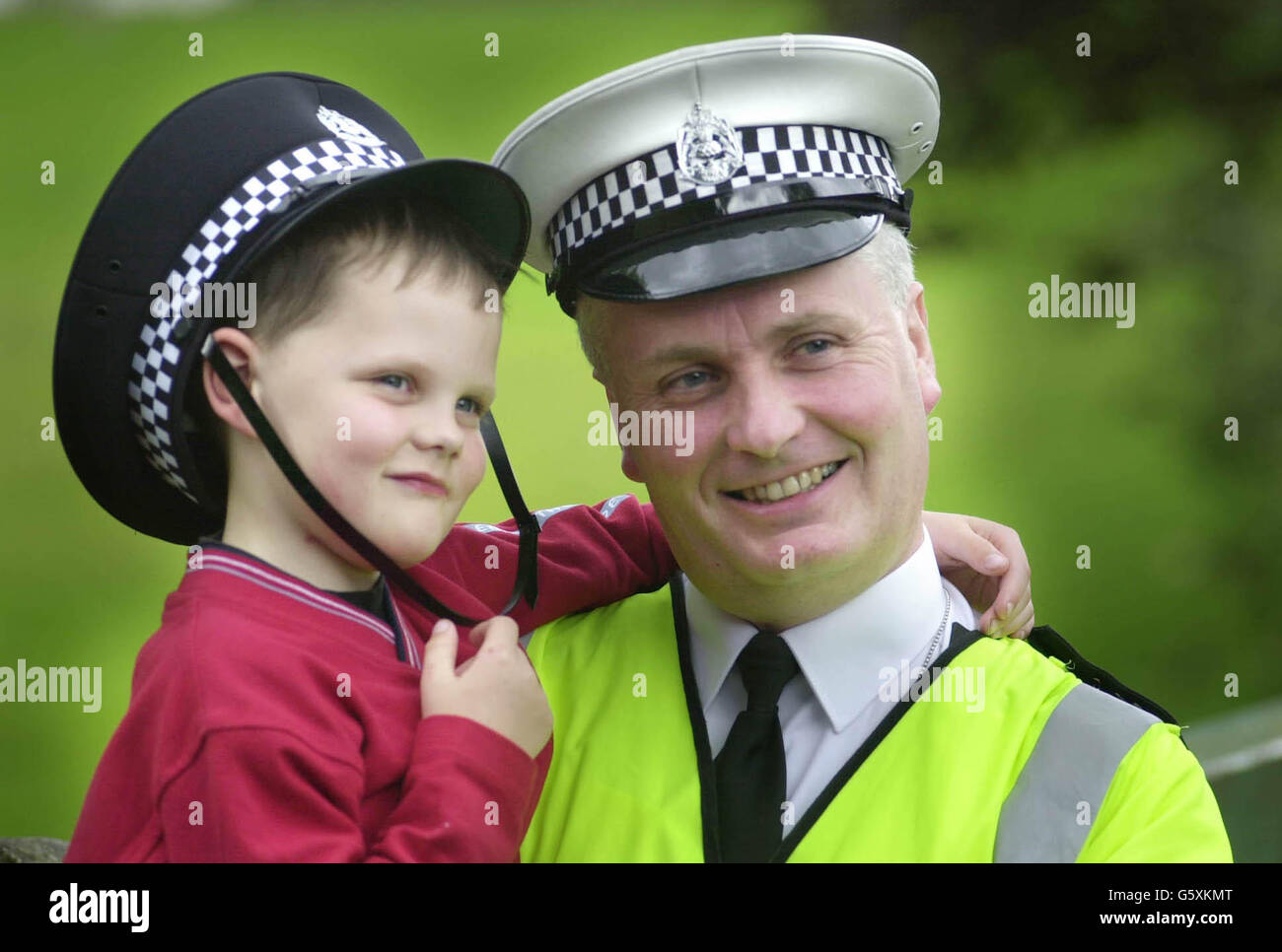 Six year old Andrew Davidson is held in the arms of Sergeant Gordon McClure, who looks to the spot where he pulled him from the Black Devon River in Clackmannan , near Stirling, after the boy fell in. Stock Photo