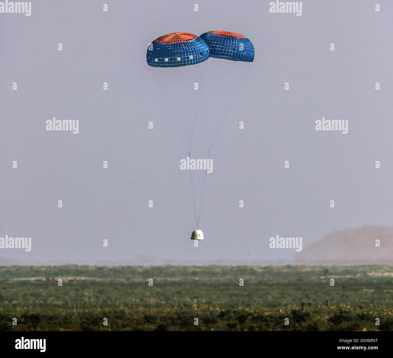 The Blue Origin New Shepard crew capsule floats safely to land following an emergency failure test after lift off into space at the west Texas proving grounds during the fourth successful test June 19, 2016 in Van Horn, Texas. This is the fourth time in a row that Blue Origin has launched and landed the same reusable rocket. Stock Photo