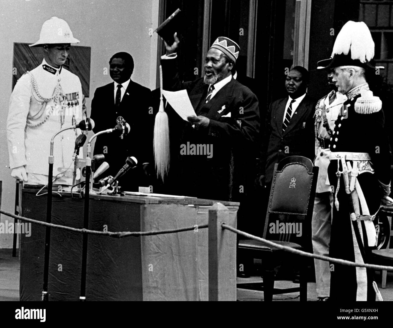 Jomo Kenyatta holding a Bible and a fly whisk swearing the oath of