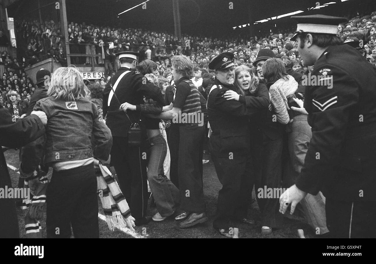 A terrified girl clings to one of the ambulanceman working among fans on the pitch at Upton Park, London, as fighting on the terraces and crowd invasion of the field caused a 19-minute stoppage of play in the match between West Ham and Manchester United. Stock Photo