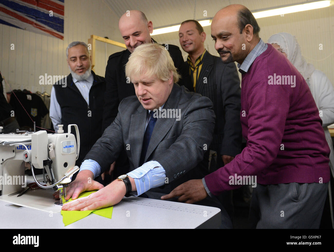 London Mayor Boris Johnson tries his hand on a sewing machine during a visit to clothing factory, East End Manufacturing in London. Stock Photo