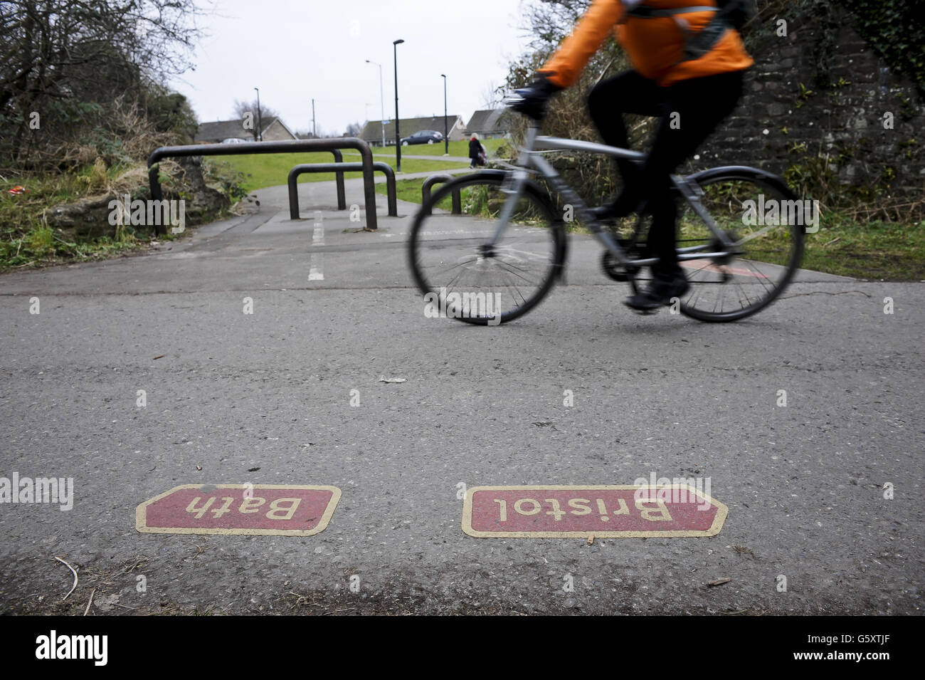 A cyclist passes Bristol and Bath direction arrows on the Bristol & Bath railway path. The Bristol & Bath Railway Path was constructed on the track bed of the former Midland Railway which closed for passenger traffic at the end of the 1960s. Between 1979 and 1986, the railway line was converted into the Railway Path by cycling charity Sustrans. The first stretch was between Bath and Bitton where the campaign group, Cyclebag obtained planning permission to create the 2m wide dust track. The route then developed westwards with Bristol being the last section. This was tarmaced from the outset. Stock Photo