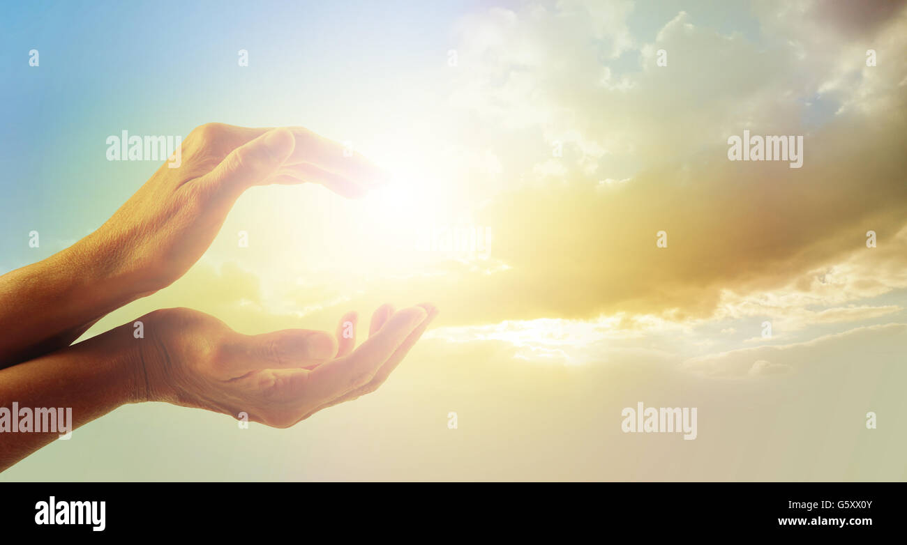 Female hands cupped with evening sunlight captured between and beautiful gentle dusk sky line and clouds in background Stock Photo