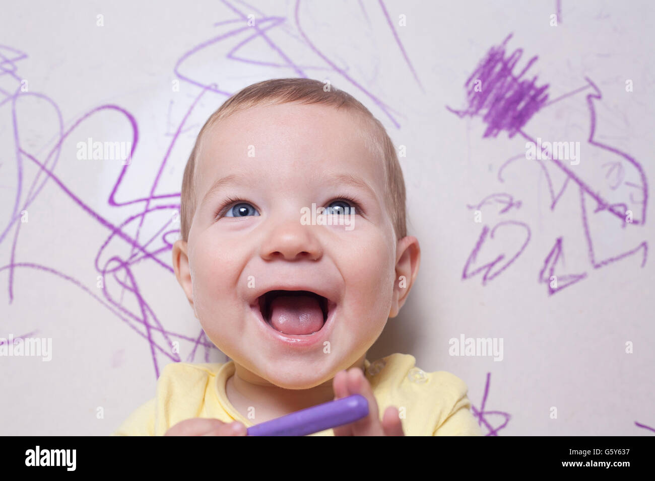 Smilling baby boy with wax crayon. He is looking to the camera Stock