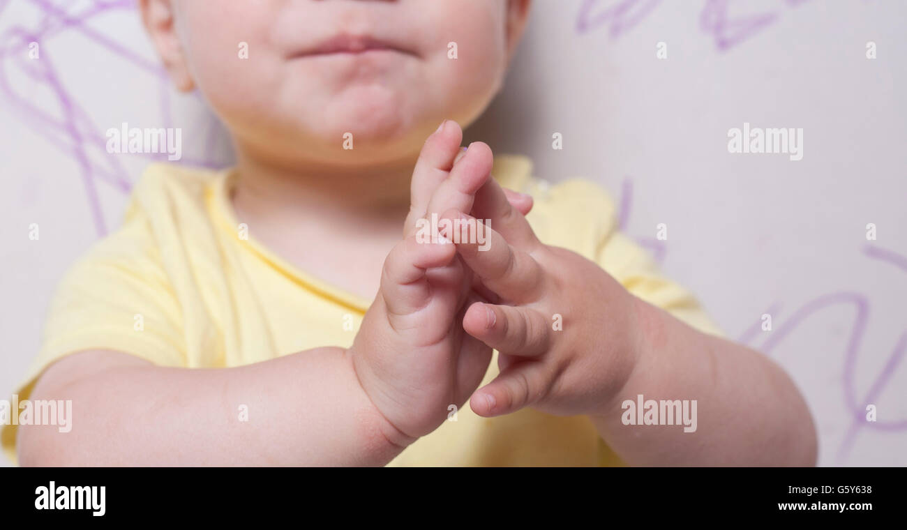 Baby boy clapping after drawing with wax crayon a plasterboard wall Stock Photo