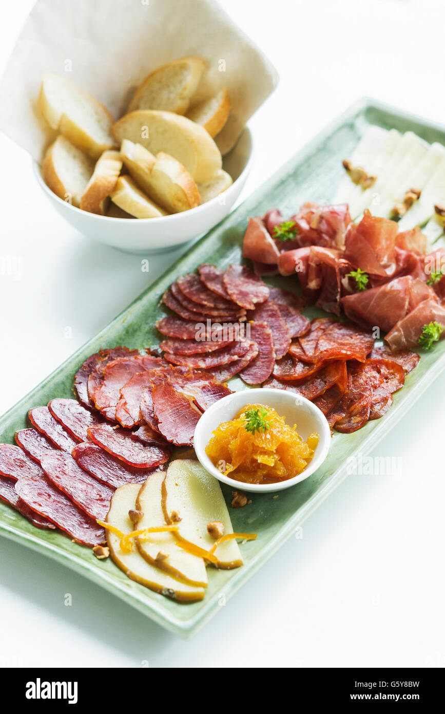 spanish serrano ham chorizo sausage smoked meats cheese tapas sharing platter set with bread Stock Photo