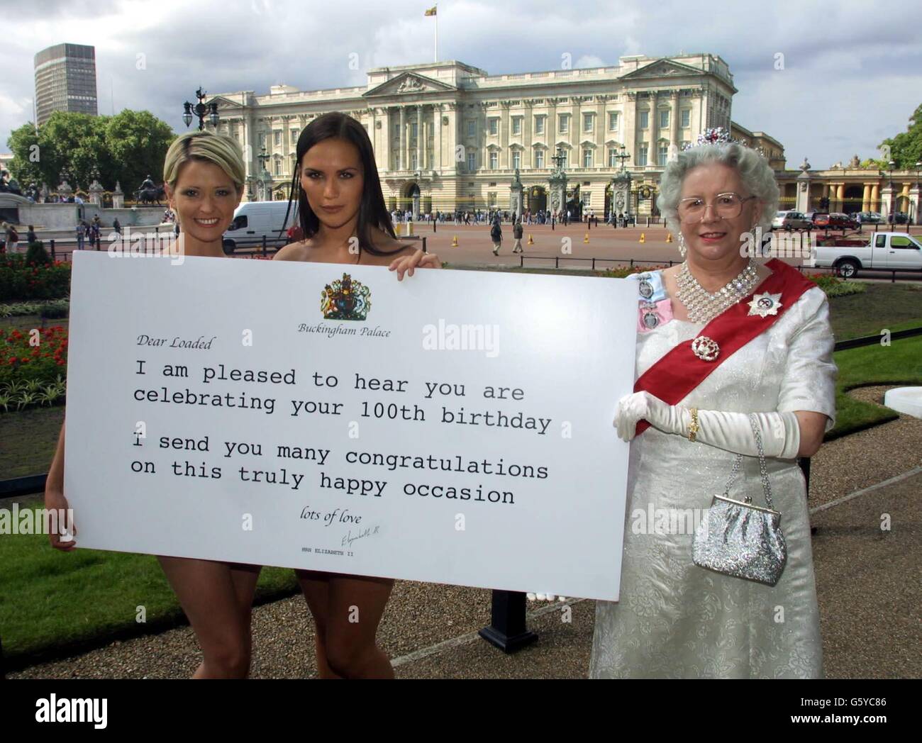 Models Lucy Clarkson (left) and Jo Guest pose are presented with a Telegram by Queen look-a-like, Margaret Southcoat during a photocall outside Buckingham Palace, to celebrate the 100th Issue of mens magazine Loaded. Stock Photo