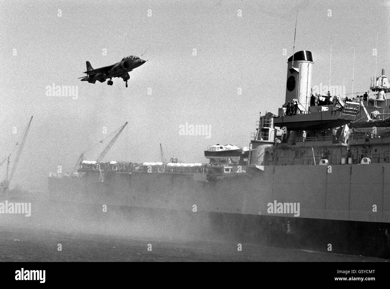 A Harrier's downward thrust raises a filmy curtain of spray as the Hawker Siddeley jump jet comes in to land on the 12,000 ton assault ship HMS Fearless, berthing at Greenwich. The ship is on a visit, and the Harrier will be in an equipment exhibition seen by delegates to the Atlantic Treaty Association Seminar taking place at the Royal Navy Staff College at Greenwich. Stock Photo