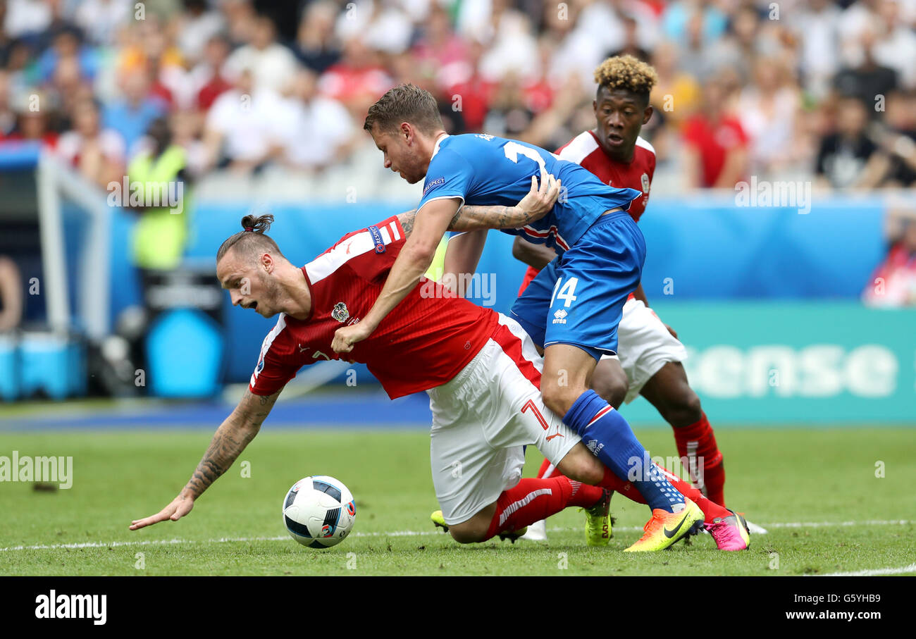 Austria's Marko Arnautovic (left) goes down under the challenge from Iceland's Kari Arnason (right) during the Euro 2016, Group F match at the Stade de France, Paris. Stock Photo