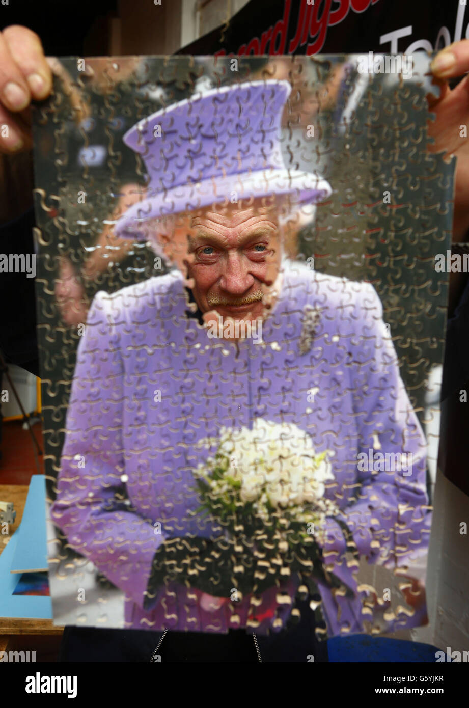 Dave Evans peers through one of his test puzzle he's cut of Queen Elizabeth II before starting to cut what he expects to be the world's largest hand cut wooden jigsaw puzzle at his workshop in Weymouth, Dorset. Stock Photo