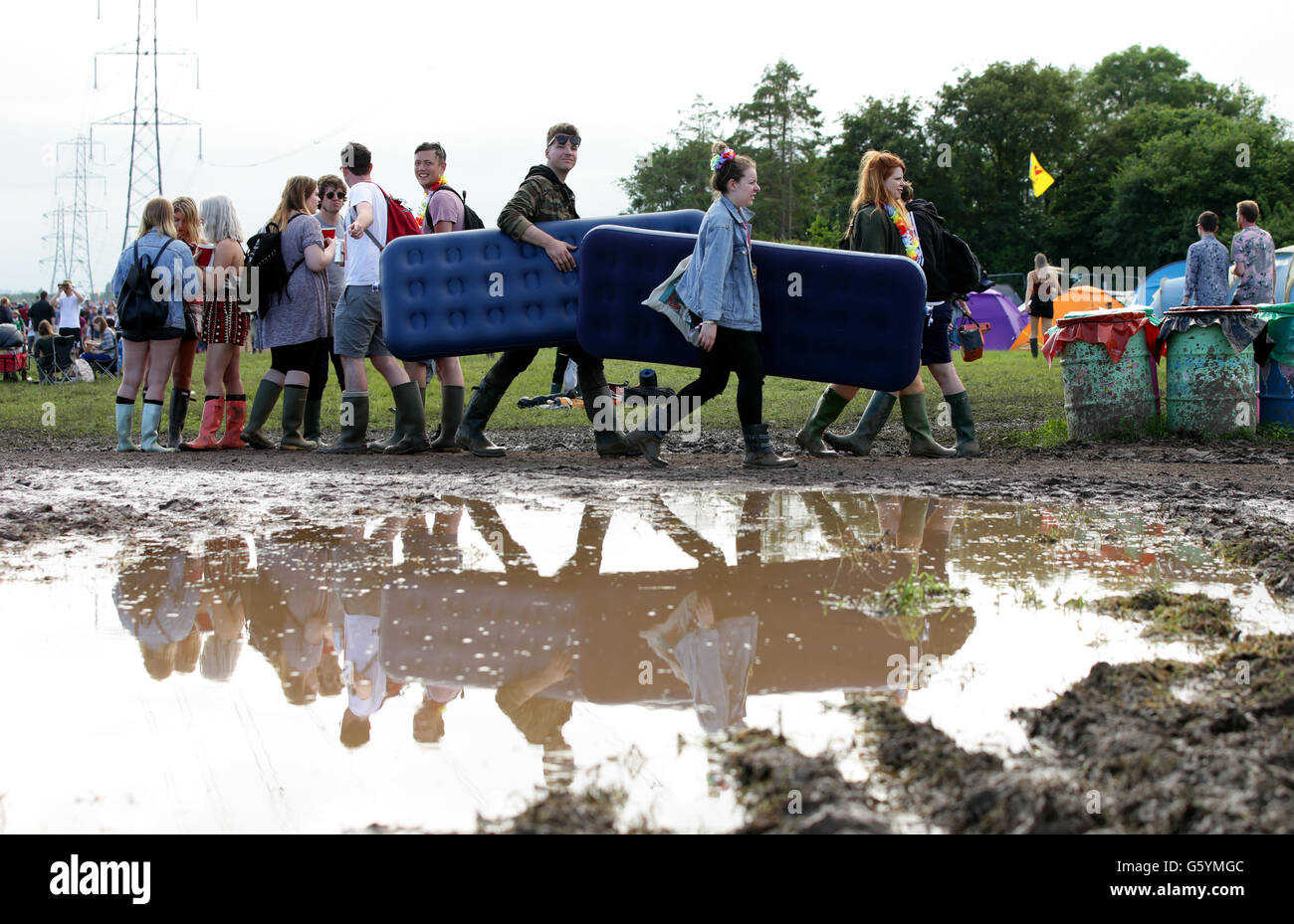 Festivalgoers carrying inflatable mattresses through the mud at the Glastonbury Festival, at Worthy Farm in Somerset. Stock Photo