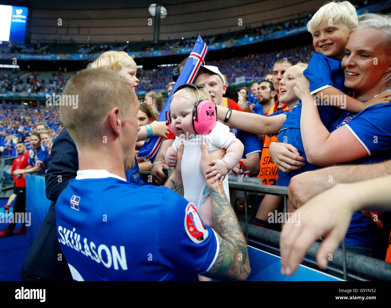 Iceland's Ari Freyr Skulason holds a baby from the crowd ...