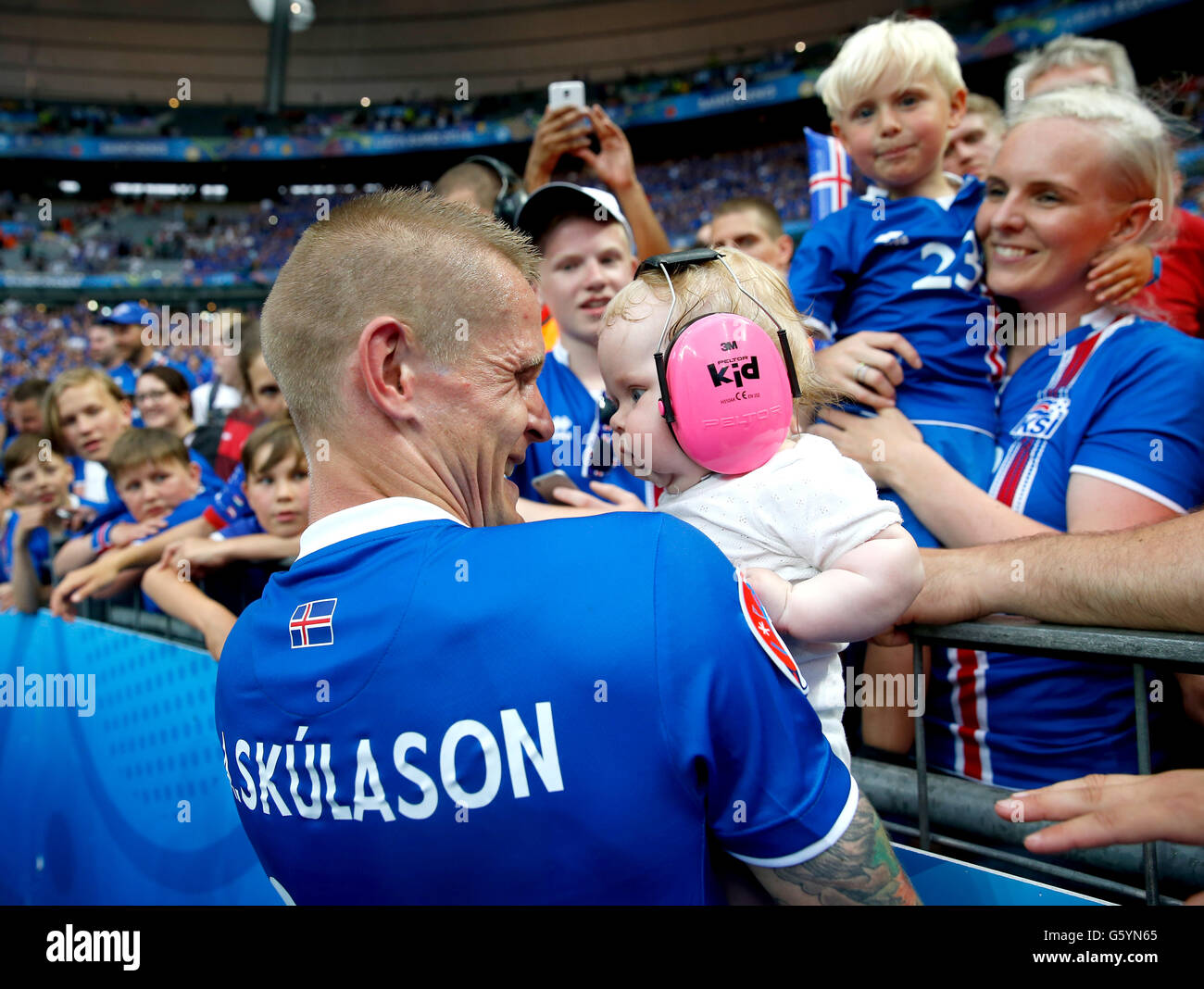 Iceland's Ari Freyr Skulason holds a baby from the crowd as he celebrates qualifying for the last 16 round after the Euro 2016, Group F match at the Stade de France, Paris. after qualifying for the last 16 round after the Euro 2016, Group F match at the Stade de France, Paris. Stock Photo