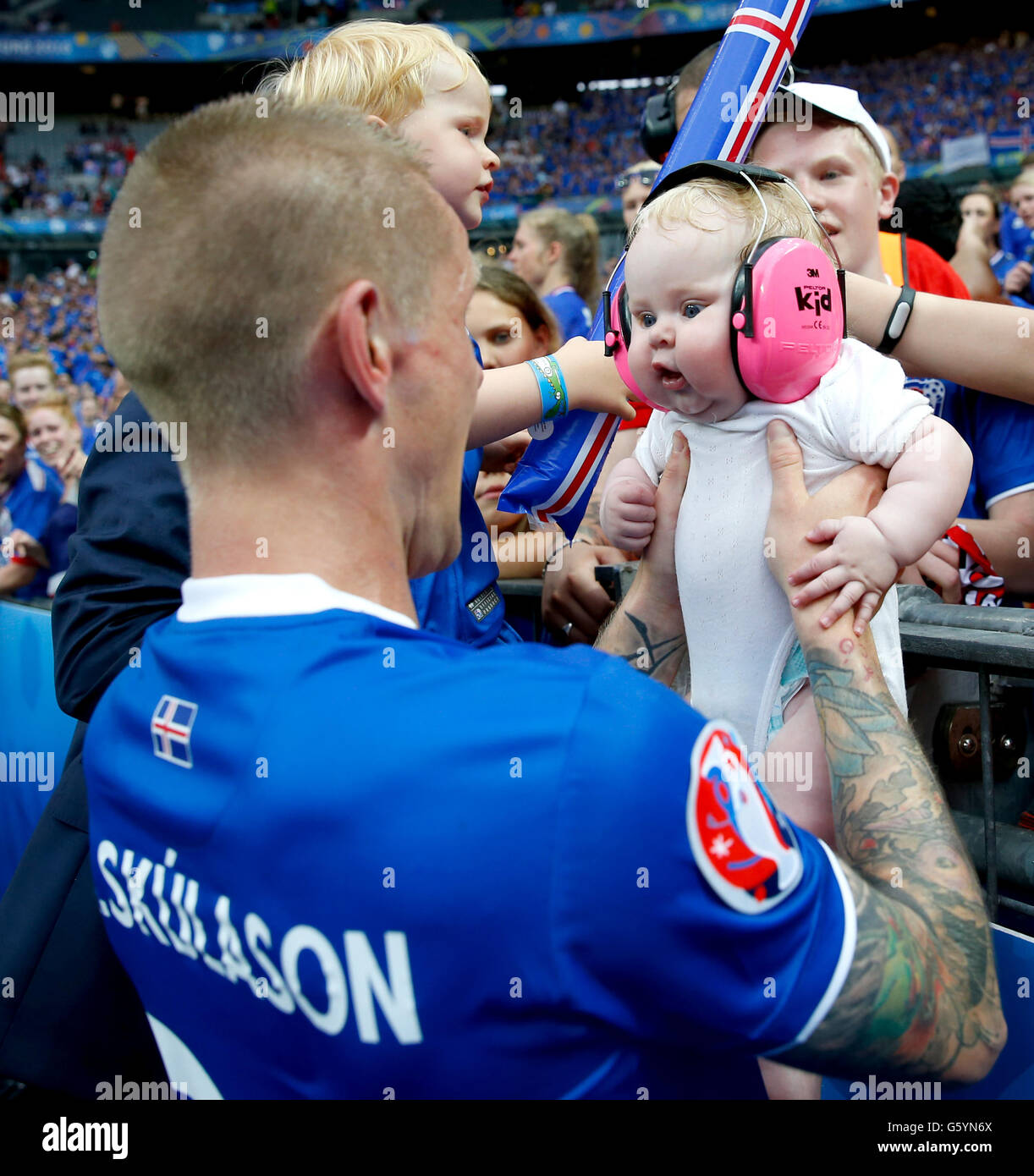 Iceland's Ari Freyr Skulason holds a baby from the crowd as he celebrates qualifying for the last 16 round after the Euro 2016, Group F match at the Stade de France, Paris. after qualifying for the last 16 round after the Euro 2016, Group F match at the Stade de France, Paris. Stock Photo