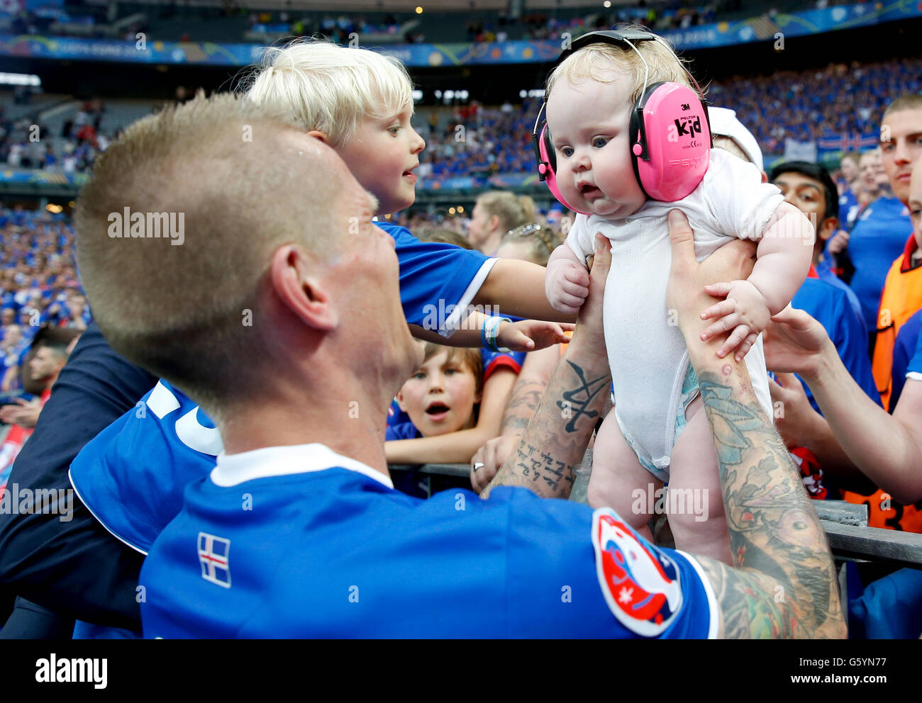 Iceland's Ari Freyr Skulason holds a baby from the crowd as he celebrates qualifying for the last 16 round after the Euro 2016, Group F match at the Stade de France, Paris. after qualifying for the last 16 round after the Euro 2016, Group F match at the Stade de France, Paris. Stock Photo