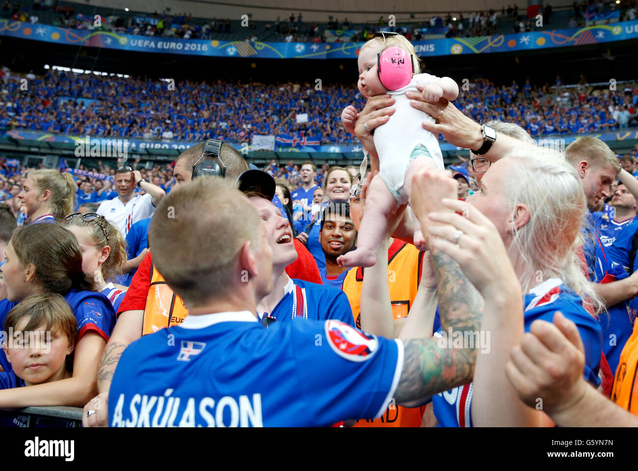 Iceland's Ari Freyr Skulason is handed a baby from the crowd as he celebrates qualifying for the last 16 round after the Euro 2016, Group F match at the Stade de France, Paris. after qualifying for the last 16 round after the Euro 2016, Group F match at the Stade de France, Paris. Stock Photo