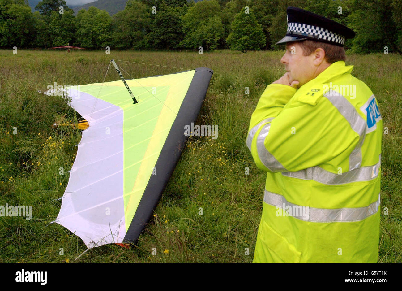 Constable Ian Carnegie from Crianlarich Police inspects the damaged hand-glider near Inverhaggernie Farm, one mile north of Crianlarich in Perthshire, Scotland. where one man died as the hanglider collided with an 11,000 volt electric power cable. * Police believe the victim to have been 42 and from Cambridgeshire. Stock Photo