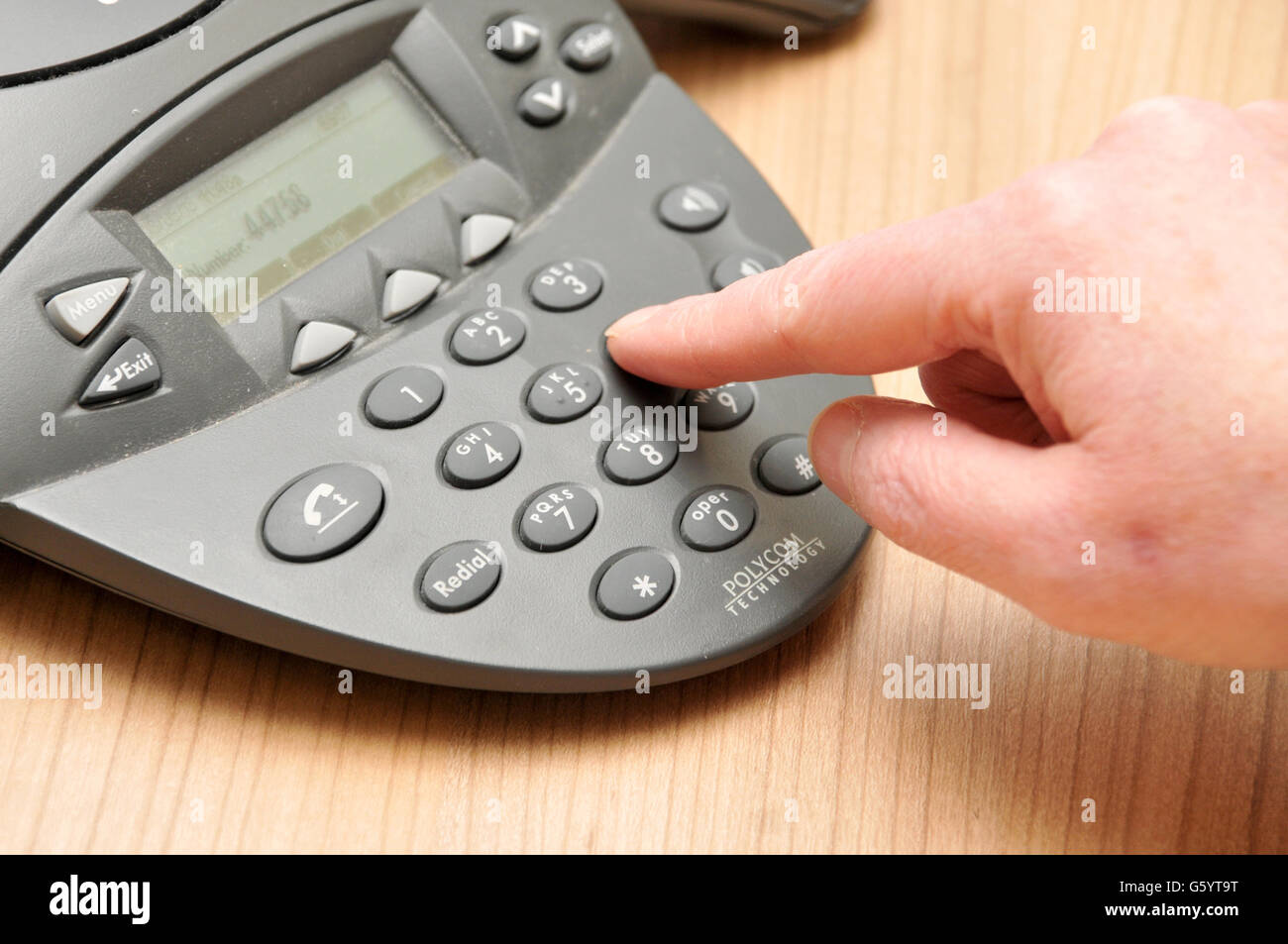 A female employee dials a telephone number on a conference call phone during a meeting Stock Photo