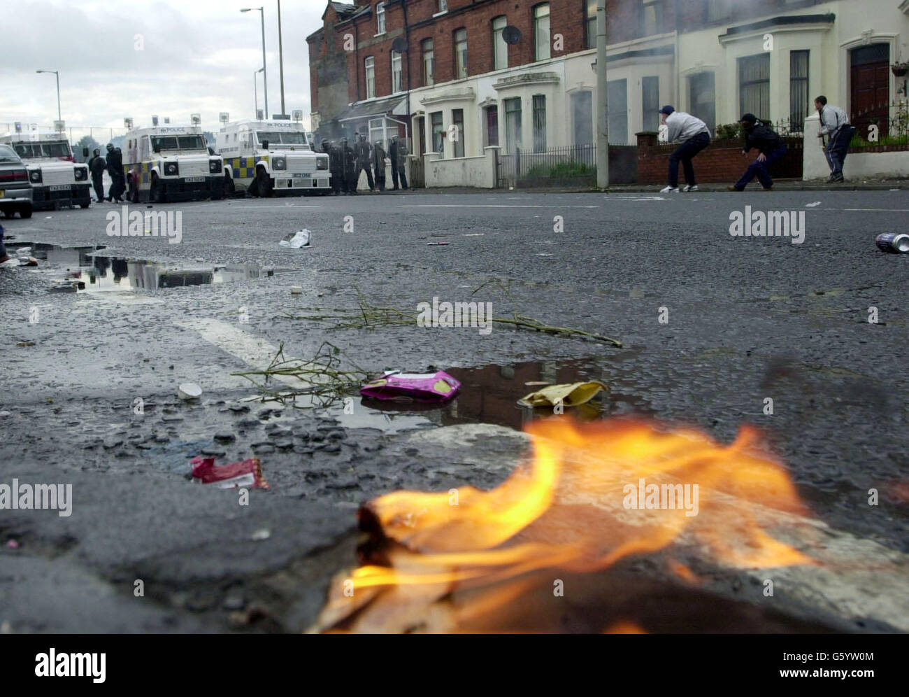 Police hold a line as Catholic youths throw stones at the bottom of the Springfield Road, west Belfast. Police suffered a barrage of petrol bombs, fireworks, and bricks after officers fired a plastic baton rounds at protesters attacking an Orange Order parade in a Nationalist area. * The trouble began when Catholic protesters saw Orangemen walking up a contested part of the Springfield Road. Stock Photo