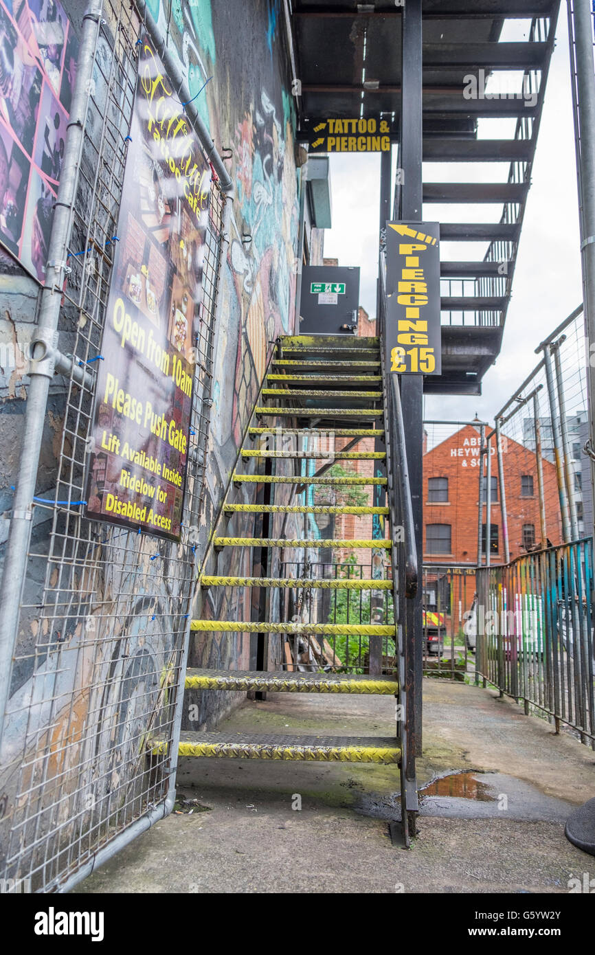 A metal staircase/ fire escape leading up to a tattoo parlor Stock Photo