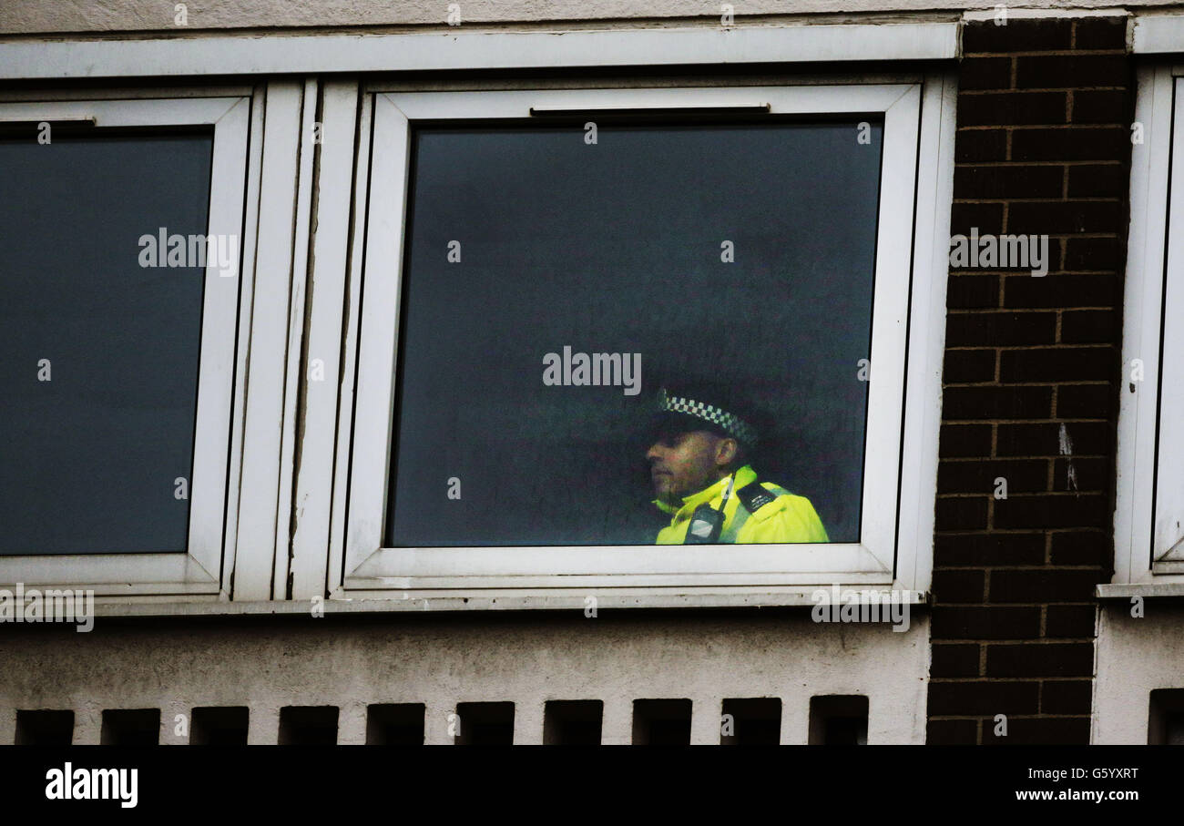 A policeman looks out from a block of flats on St Andrew's Drive in Glasgow after a four-year-old boy has died after falling from a window. Stock Photo