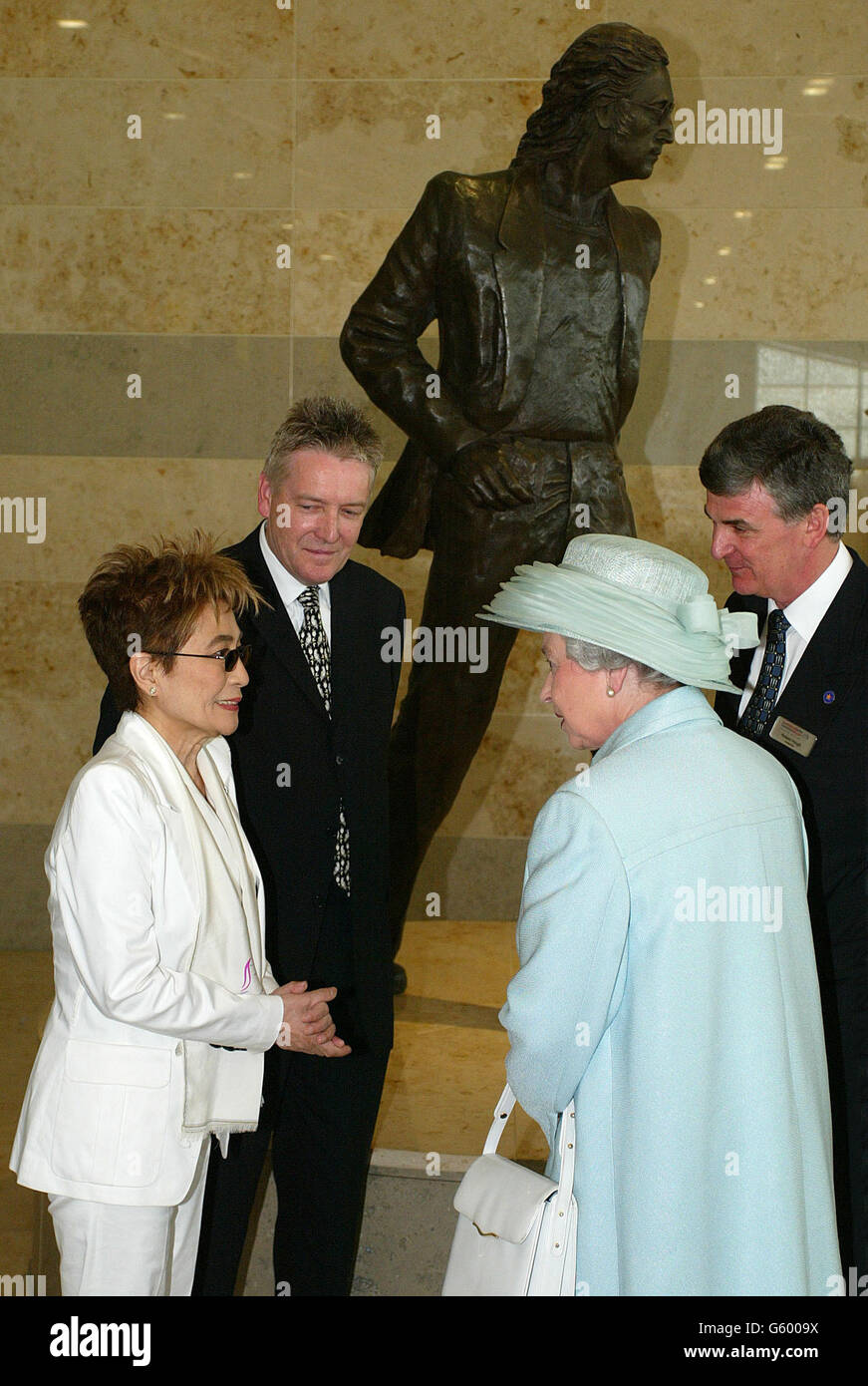 Britain's Queen Elizabeth II talks with Yoko Ono, in front of a statue - designed by Tom Murphy (centre) - of her husband, former Beatle John Lennon and airport Managing Director Robert Hough (right). They met when the Queen officially opened a 32 million passenger terminal at the airport named in his honour as she continued her Jubilee tour of the North West. Later in the day she was due to open the Commonwealth Games in Manchester. Stock Photo