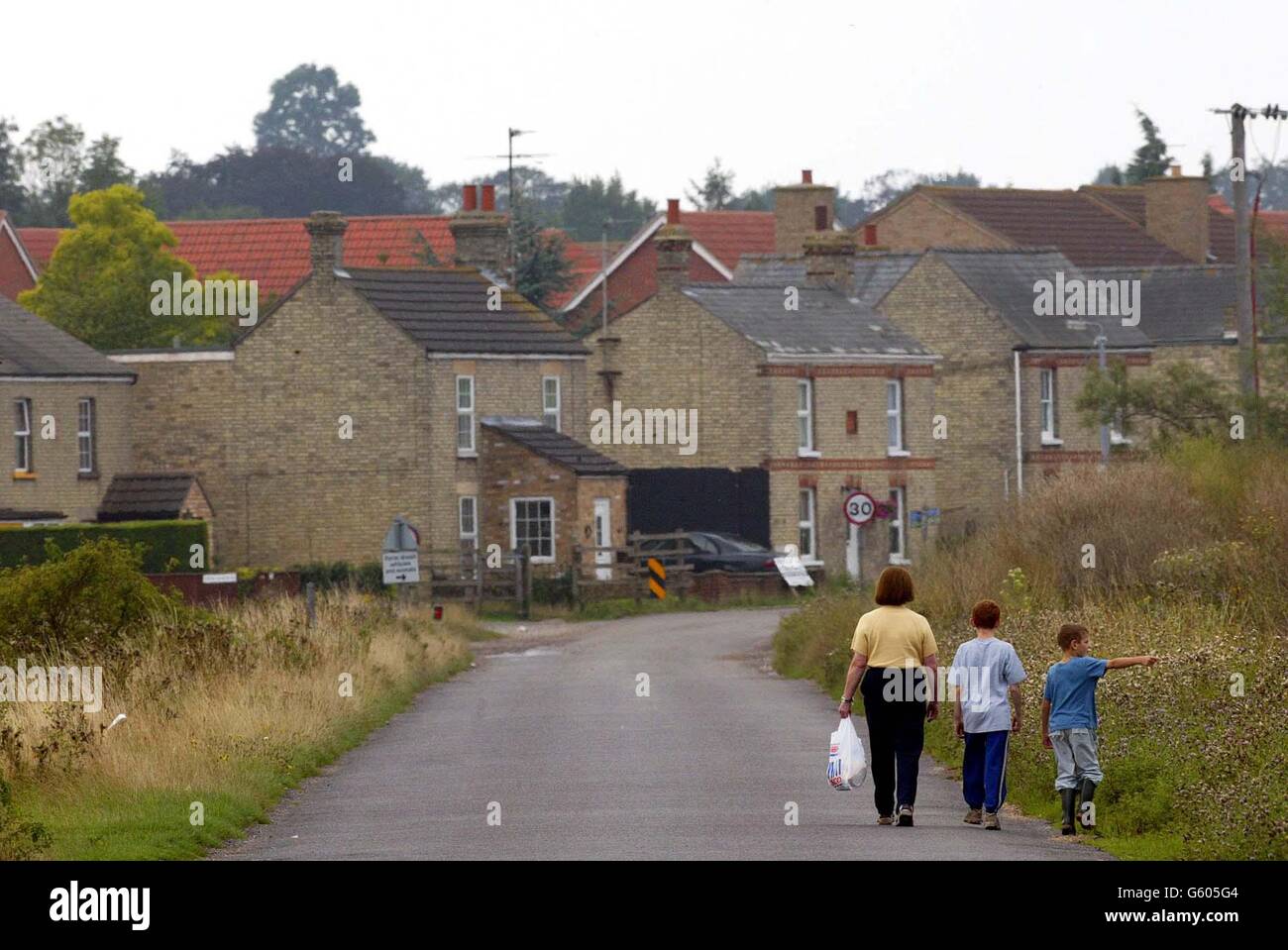 A woman walks along a country road into Soham, Cambridgeshire as the search for the missing 10-year-old girls, Holly Wells and Jessica Chapman continues. The two girls went missing on Sunday August 4 2002. *... Police have been focusing on sightings of the pair around Soham, where the girls disappeared. Officers are continuing house-to-house inquiries and have begun searching outlying areas of the town, including fields, ditches, drains and waterways. Torrential rain has lashed the town in the past 48 hours and officers have admitted they fear vital evidence could be washed away. Stock Photo