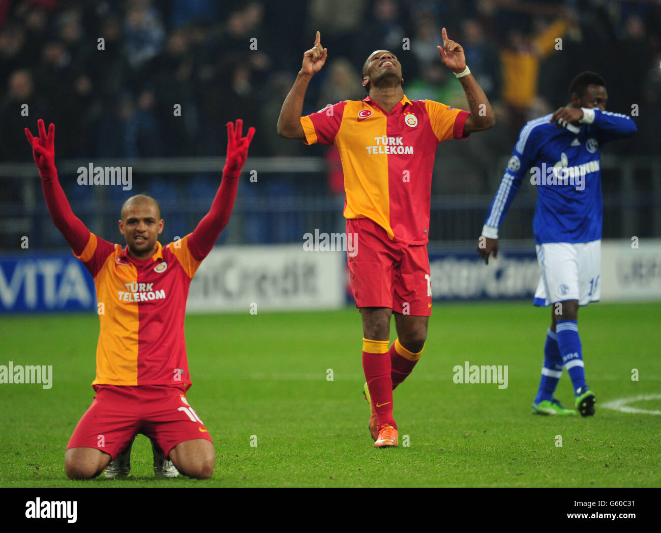 Galatasaray's Didier Drogba (centre) and Felipe Melo (left) celebrate at the end of the game as Schale 04 Michel Bastos stands dejected Stock Photo