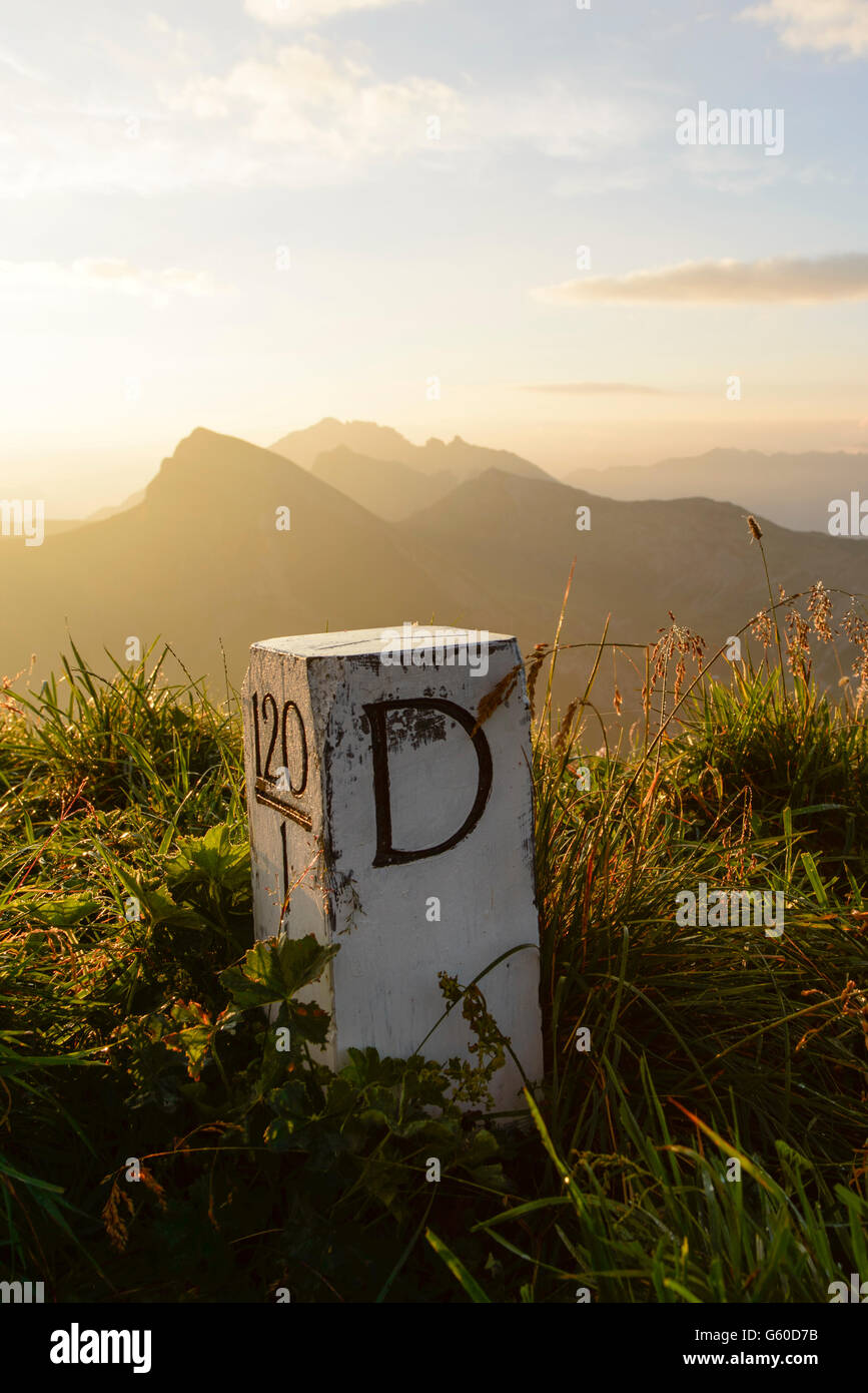 Boundary stone in the Allgäu Alps between Germany and Tyrol in Austria in autumnal evening light. Stock Photo