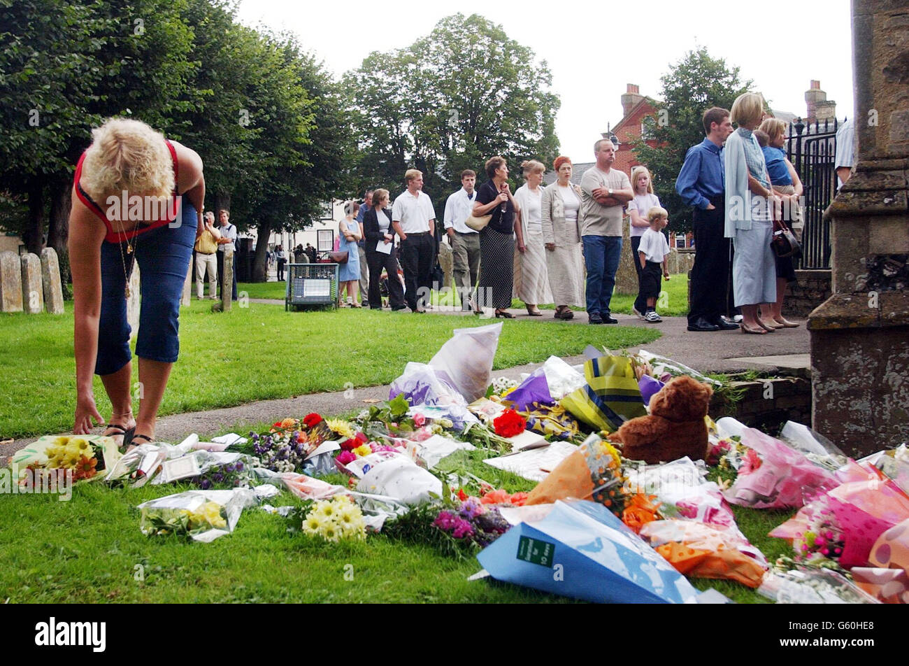 A woman leaves flowers as people queue outside St Andrew's Church, Soham, Cambridgeshire for the church service of missing girls, Holly Wells and Jessica Chapman. *The local church in the home village of Holly and Jessica was filled to capacity today for a special service for the schoolgirls, feared dead after the discovery of two bodies. Stock Photo