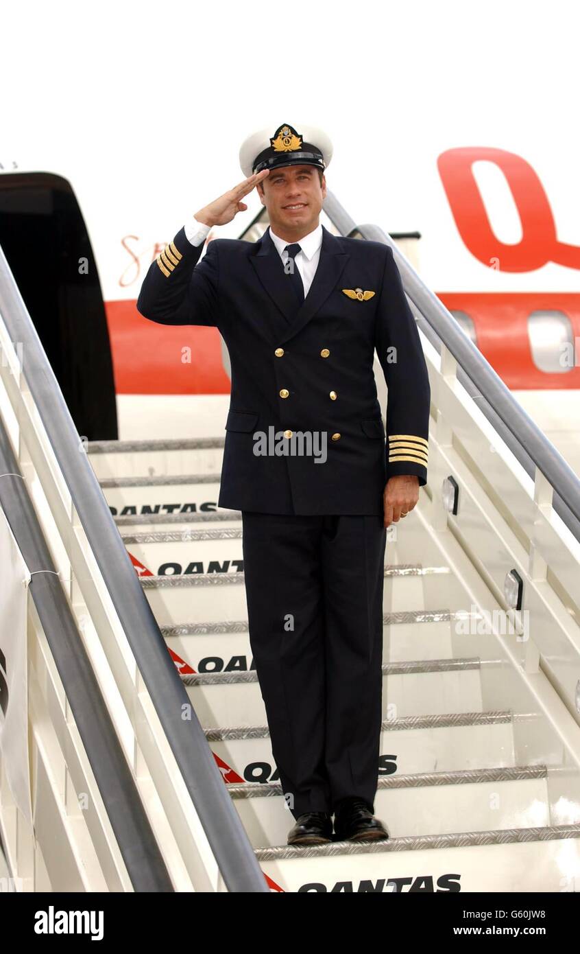 American actor John Travolta salutes on the stairs of his own 707 jet during a photocall at London's Heathrow Airport, as part of his 13-city 'Spirit of Friendship tour' as the official Qantas 'Ambassador-at-Large'. Stock Photo
