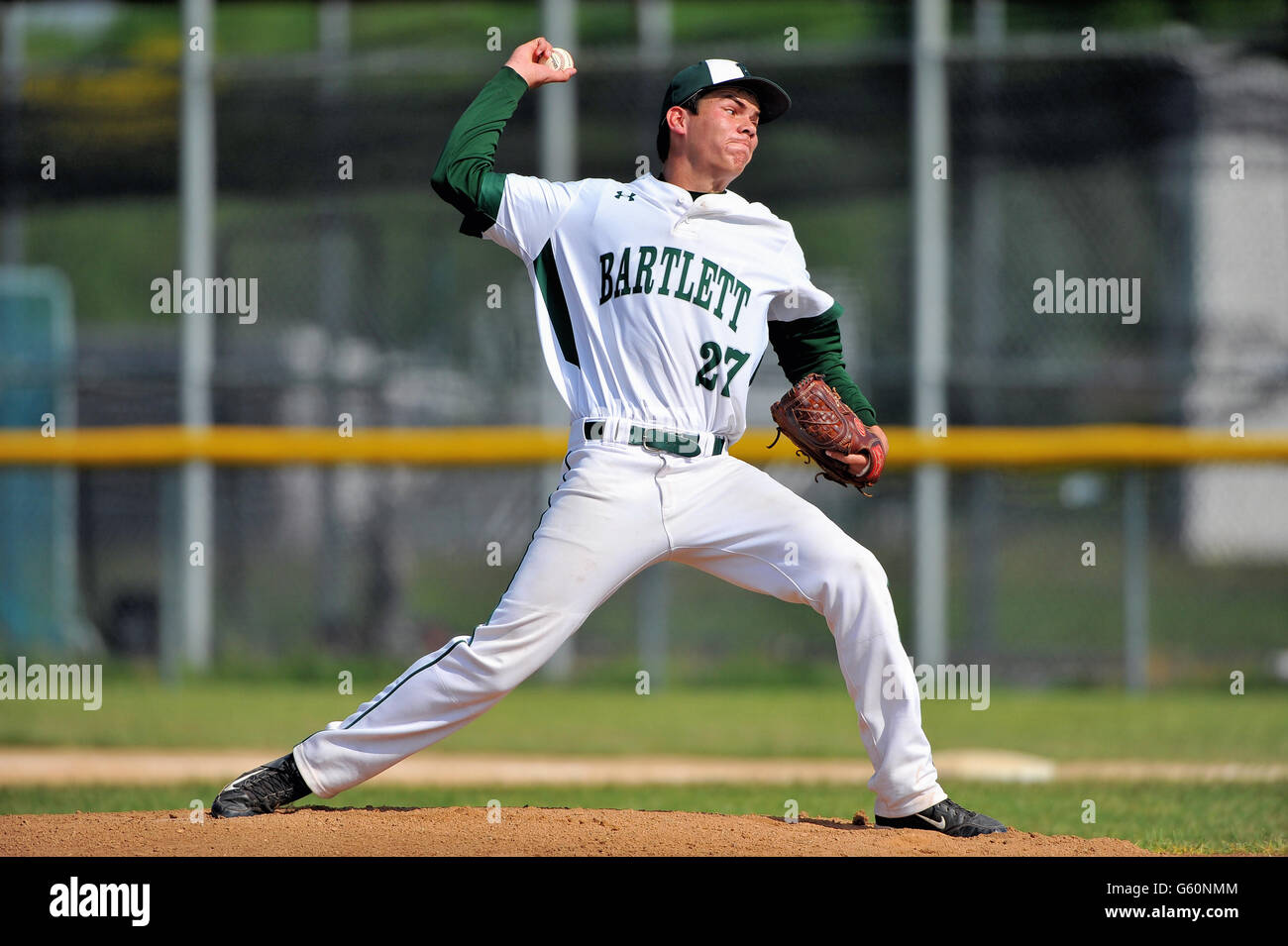 Right-handed pitcher delivering a pitch to a waiting hitter during a high school baseball game. USA. Stock Photo