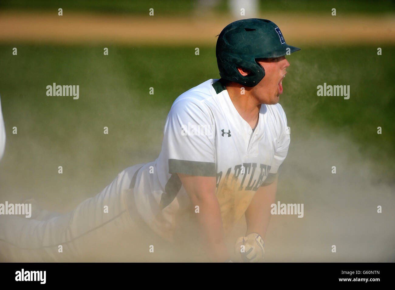 High school player diving head first safely into third base with a