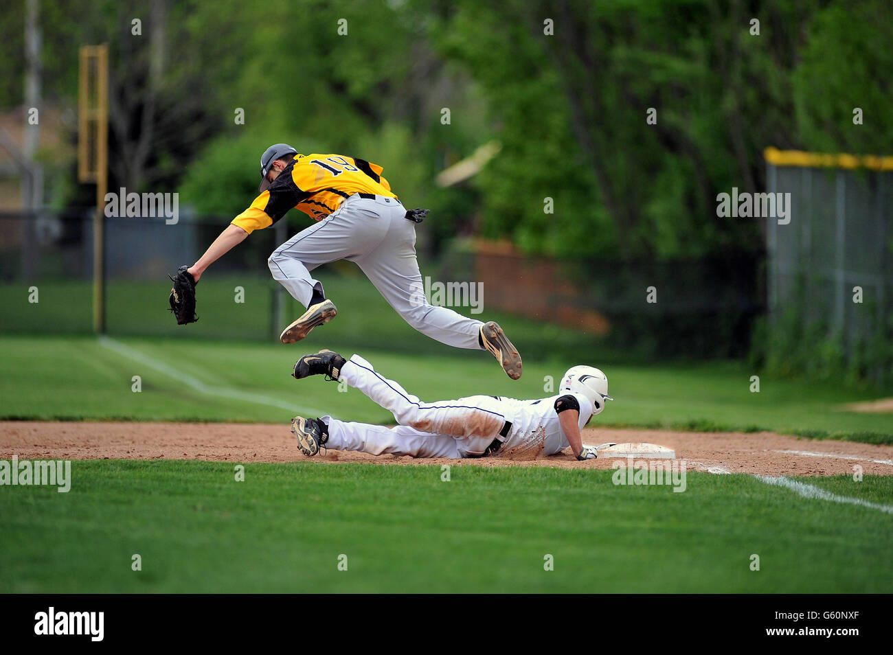 First baseman leaping over a diving base runner to catch an errant pick