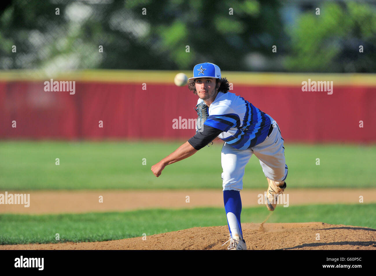 Lefthanded pitcher delivering a pitch to a waiting hitter during a