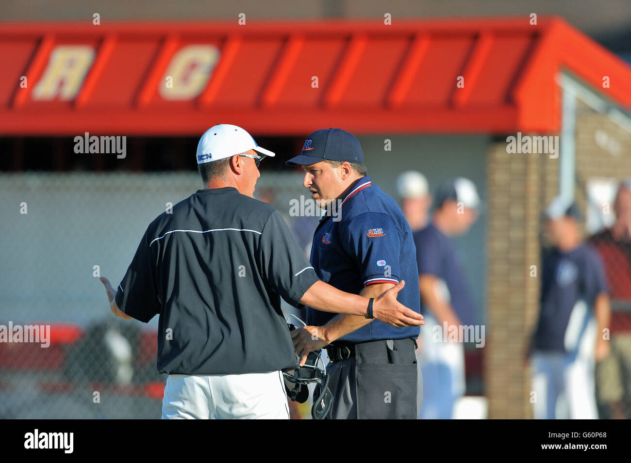 Coach arguing a call and requesting an explanation from an umpire during a high school baseball game. USA. Stock Photo