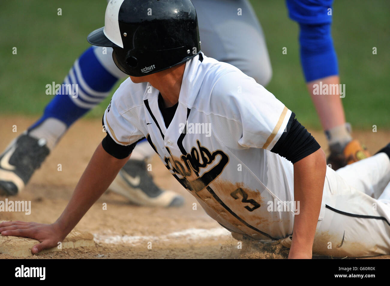 High school player diving head first safely into third base during an attempted pick-off play. USA. Stock Photo
