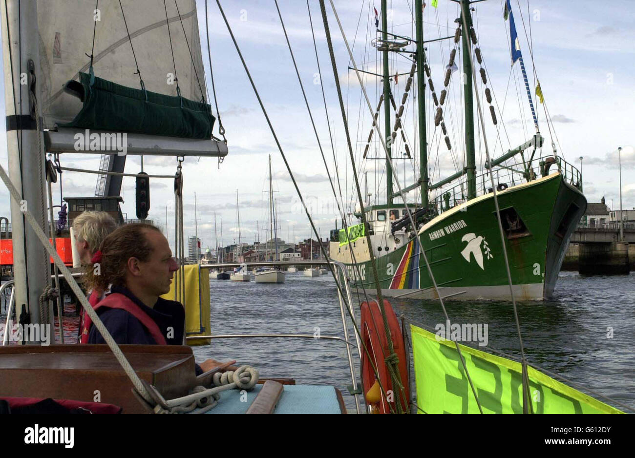 Keith White from Dublin watches Greenpeace's Rainbow Warrior (right) as it leads a flotilla of boats out of Dublin Harbour.The flotilla is protesting against a nuclear shipment bound for the Sellafield nuclear reprocessing plant in the UK, from Japan. A long line of celebrities including Bob Geldof and Ali Hewson, wife of U2 frontman Bono, have already campaigned against Sellafield and the nuclear shipment. Stock Photo